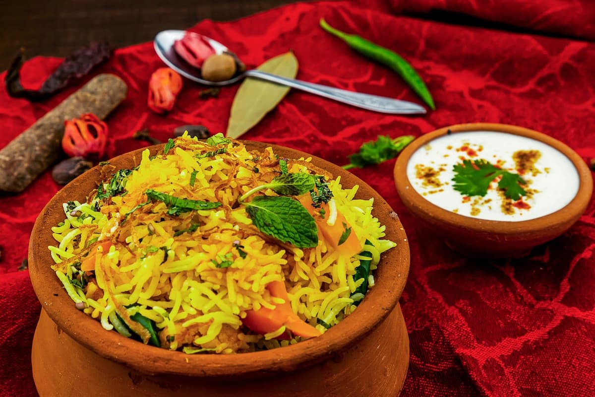 Chicken biryani served in a terracotta handi on a deep red cloth